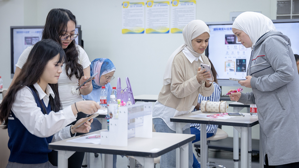 De jeunes femmes internationales apprennent à utiliser les outils d'IA pour promouvoir et présenter des produits dans des magasins en ligne à Yiwu, province du Zhejiang, le 22 avril 2025. /VCG